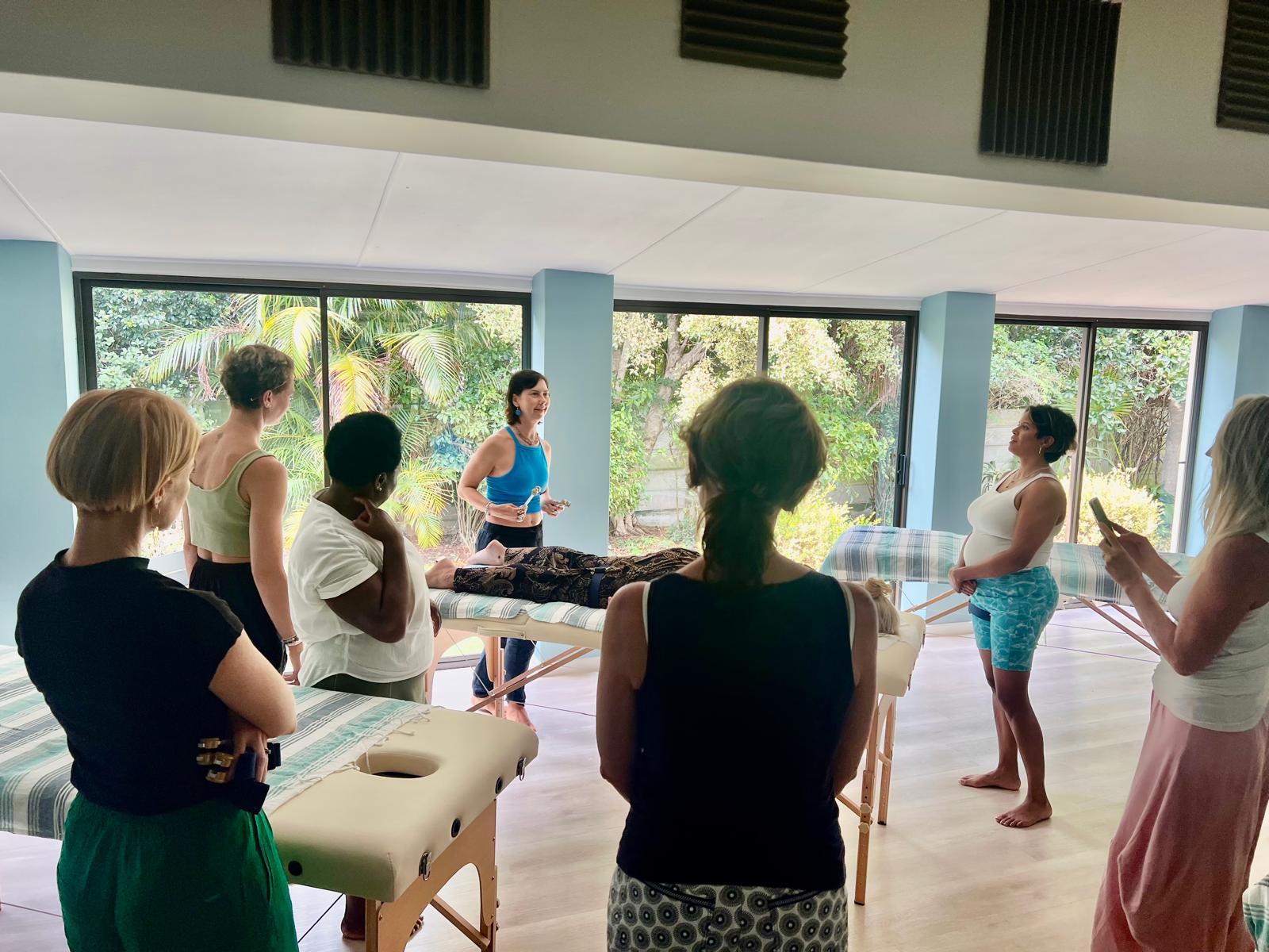Amanda Lamprecht teaching Acutonics training with students around massage tables