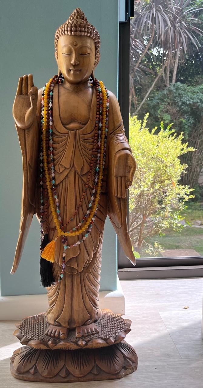 Carved wooden Buddha statue adorned with mala beads in the training space