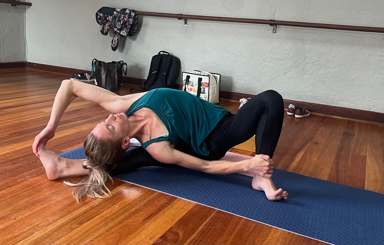 Trainee practising a reclined spinal twist during yoga teacher training