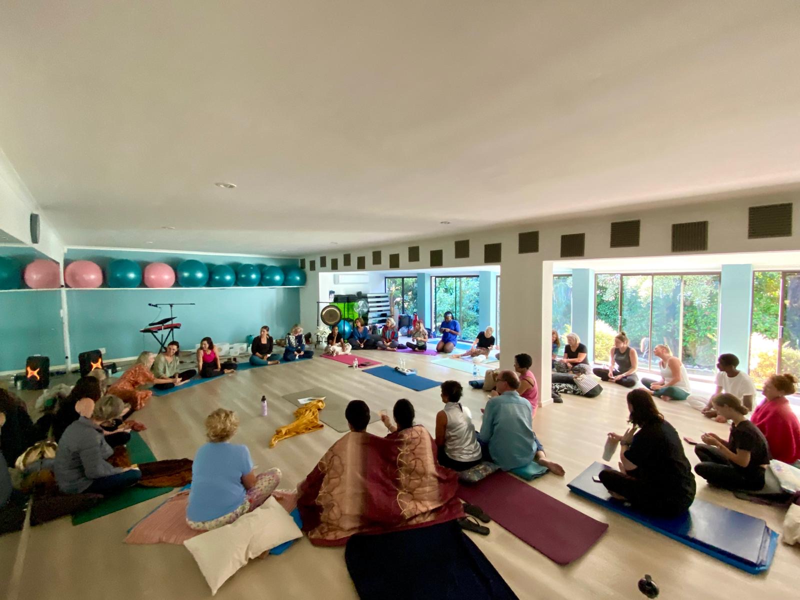 Yoga teacher training group gathered in a circle for discussion in the studio